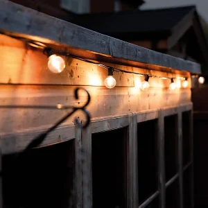 A TCP LED festoon light lit up around a house at night