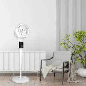 A white pedestal floor fan standing beside a grey chair
