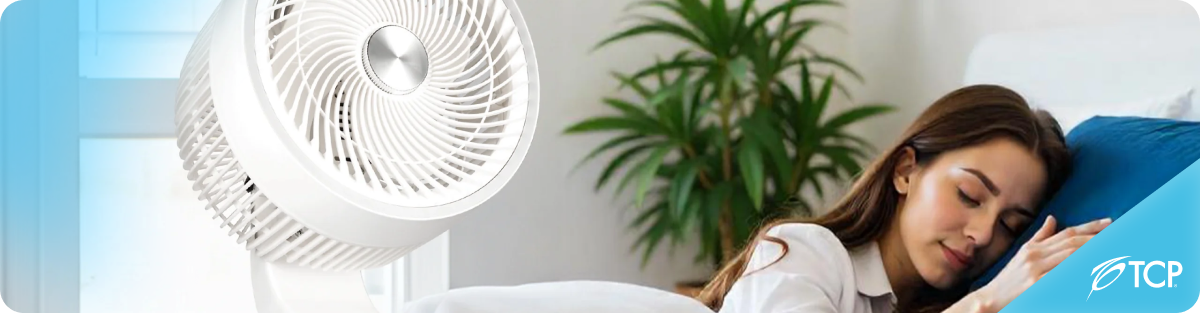A woman sleeping clise to a floor standing fan